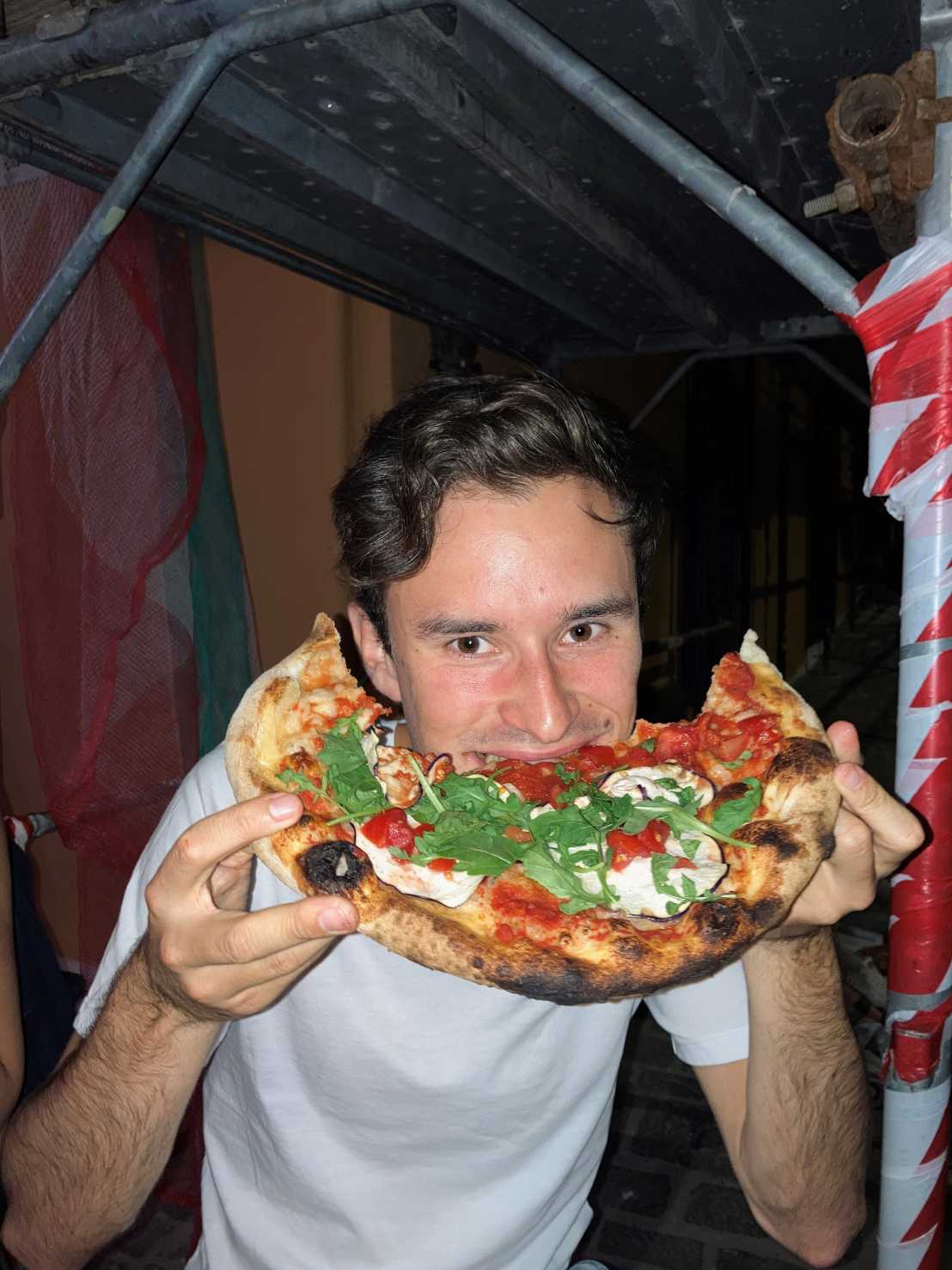 junger Mann beisst in grosse Pizza